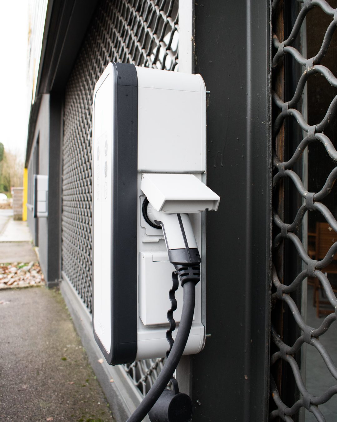 Borne de recharge murale branchée devant une façade